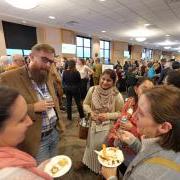 People mingle in a large conference hall.